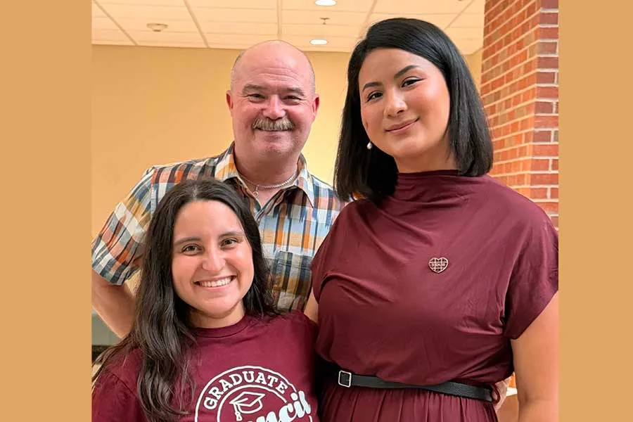 Two graduate students posing with grad school administrator