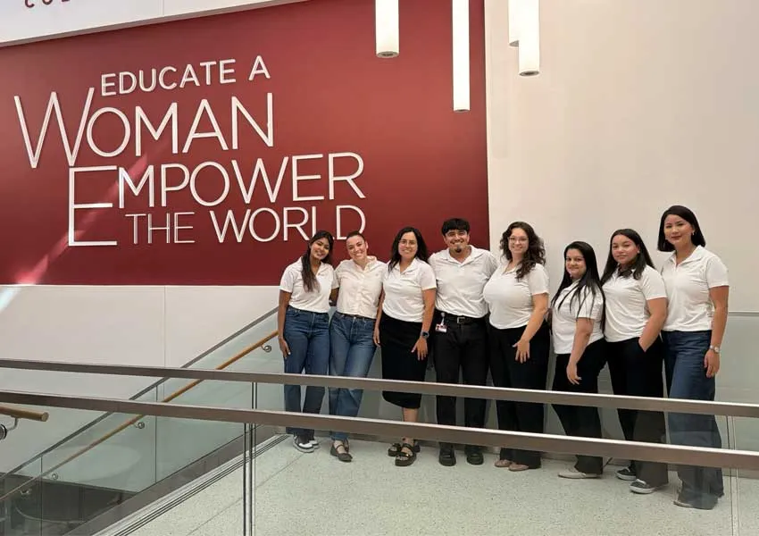 Graduate Student Council members pose next to Educate a woman sign 