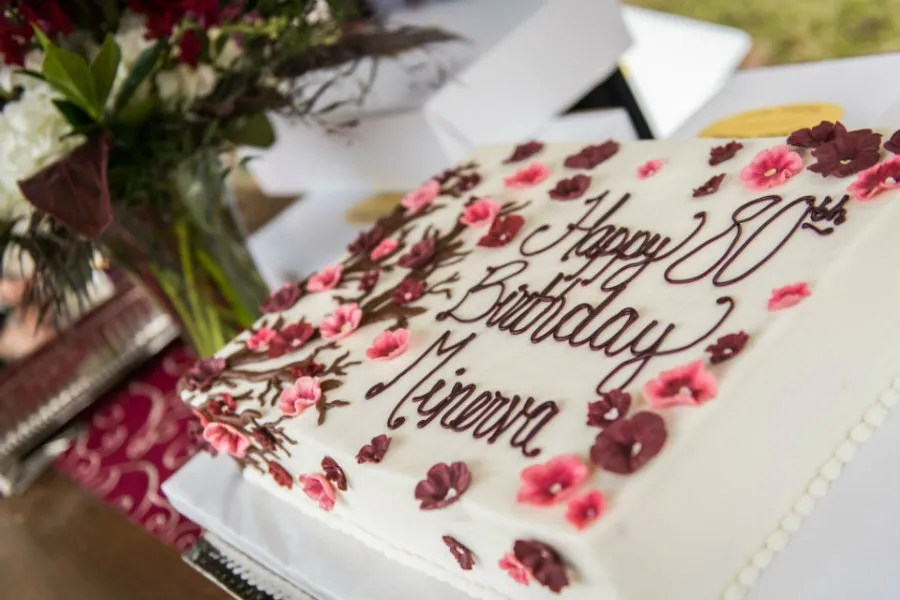 A close-up of a birthday cake decorated with redbud flowers and branches. 