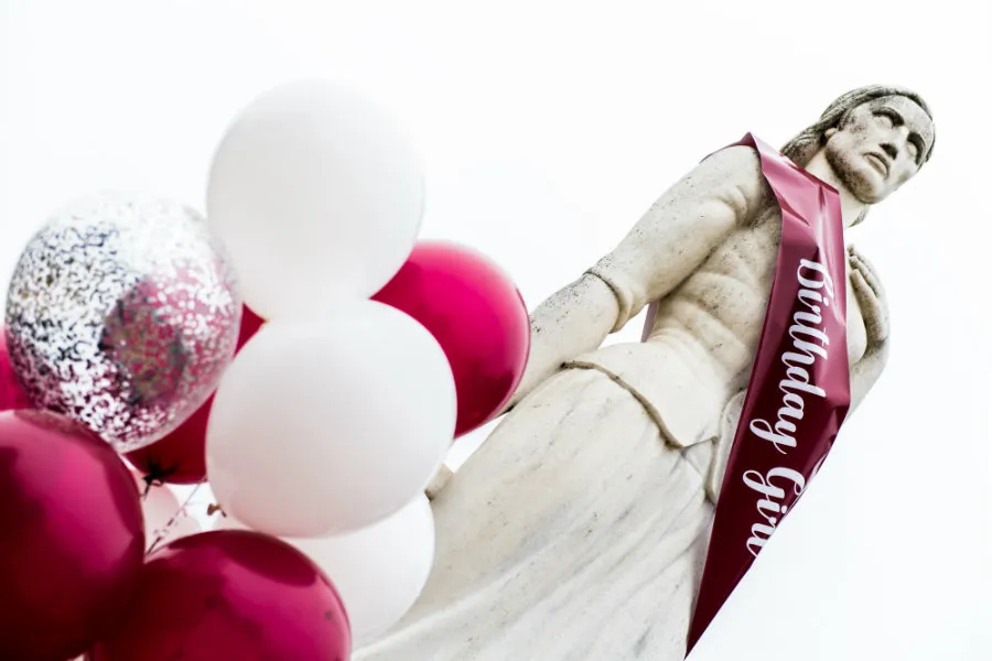 A close-up of Minerva wearing a Birthday Girl sash with balloons to her left.
