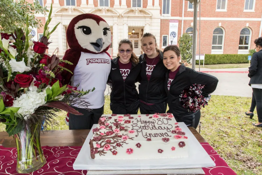 Oakley and three Pioneer Pride dance team members pose in front of Minerva's birthday cake.