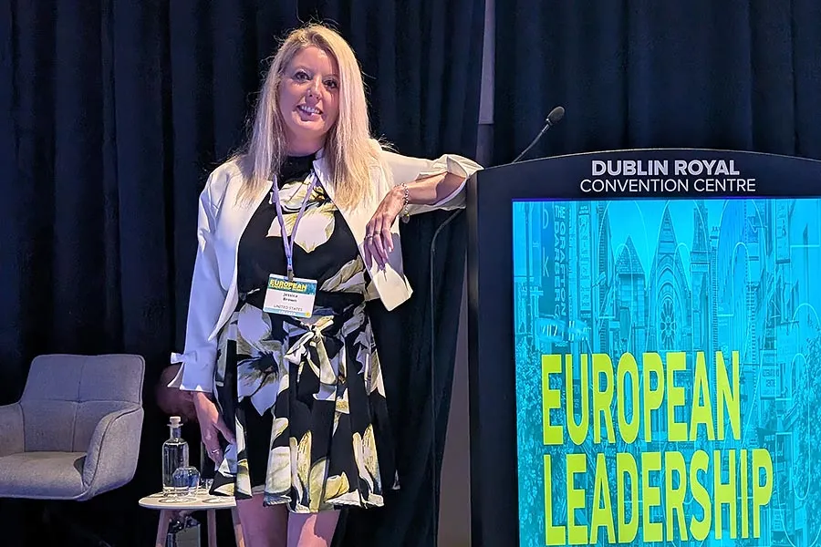 MHA/MBA student Jessica Brown leans on a European Leadership Summit banner