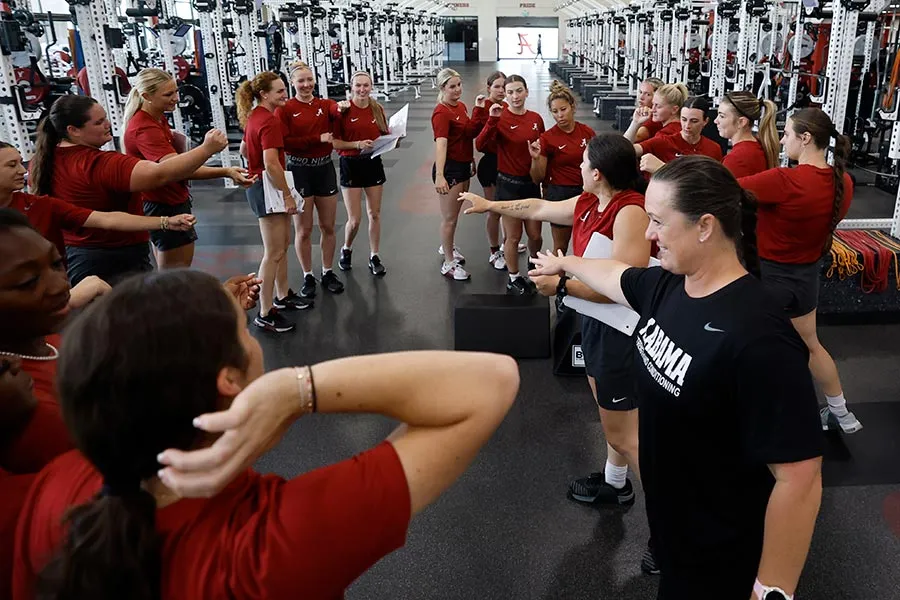 Michelle Diltz stands as part of a circle, hand in, with a group of female athletes
