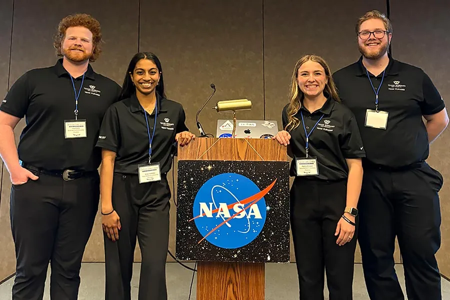 four students in TWU black polos stand next to a podium with NASA logo on front