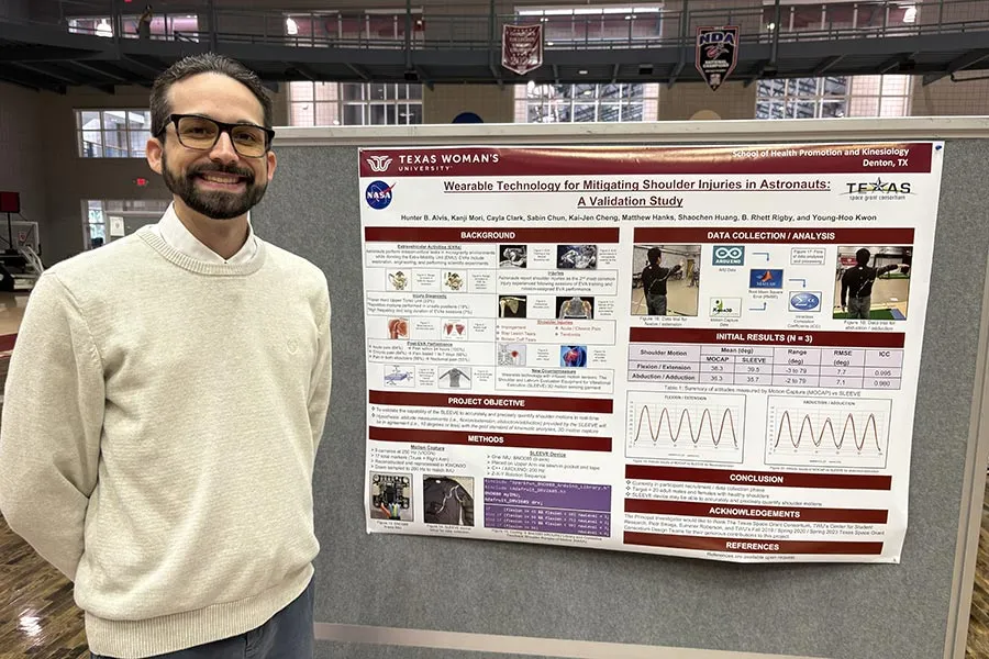 TWU student Hunter Alvis stands next to his dissertation poster project