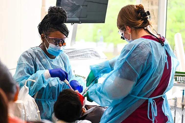 two dental hygiene students clean a child