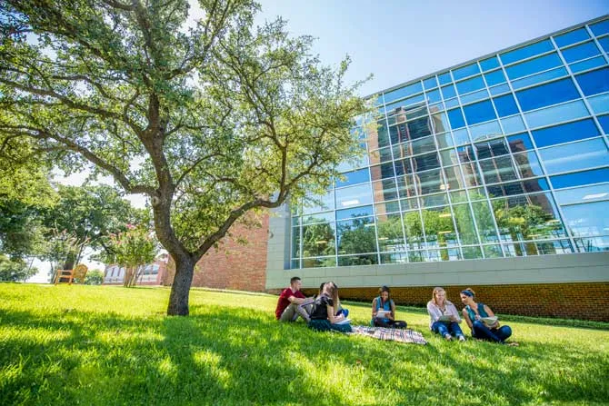 TWU students sitting on the grass near the Fit & Rec building