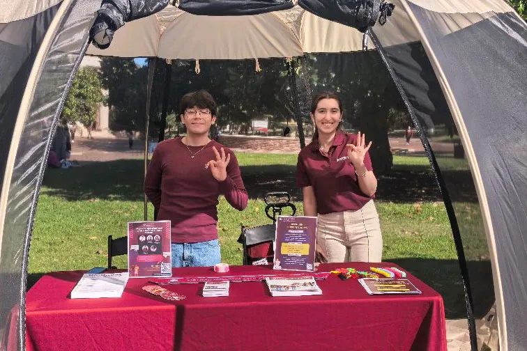 Students flashing the TWU hand sign at a tabling event.