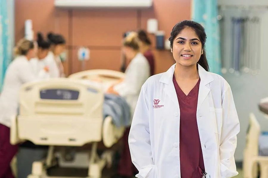 A TWU nursing student stand apart from a crowd in a hospital setting.
