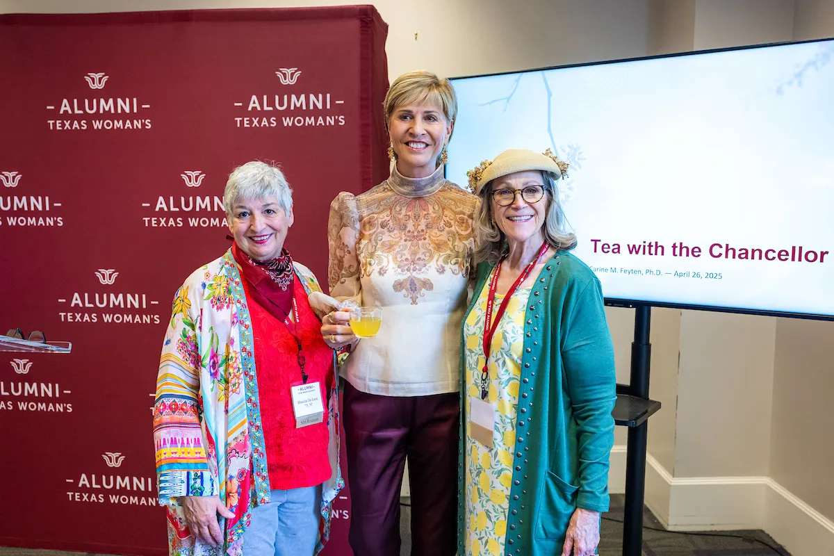 Chancellor Feyten poses with two alumni at the tea.