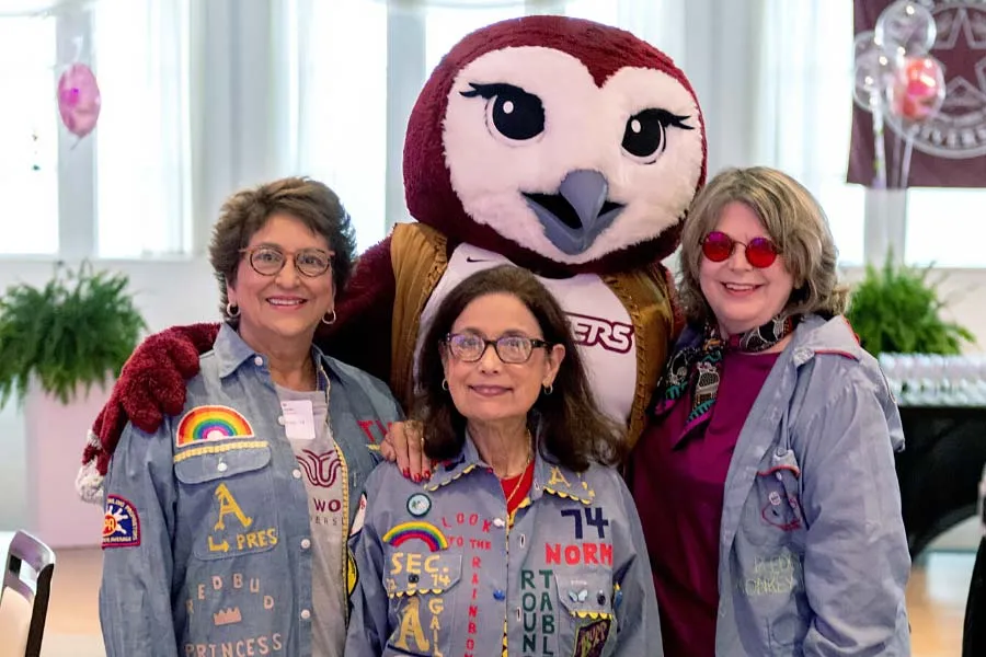 Three TWU alums pose with mascot Oakley