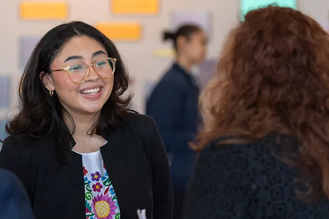 Two alumni in business apparel talk and smile.