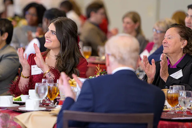 TWU alumni and friends sit at an upscale plated dinner, turning and applauding at the Alumni Achievement Awards presentation.