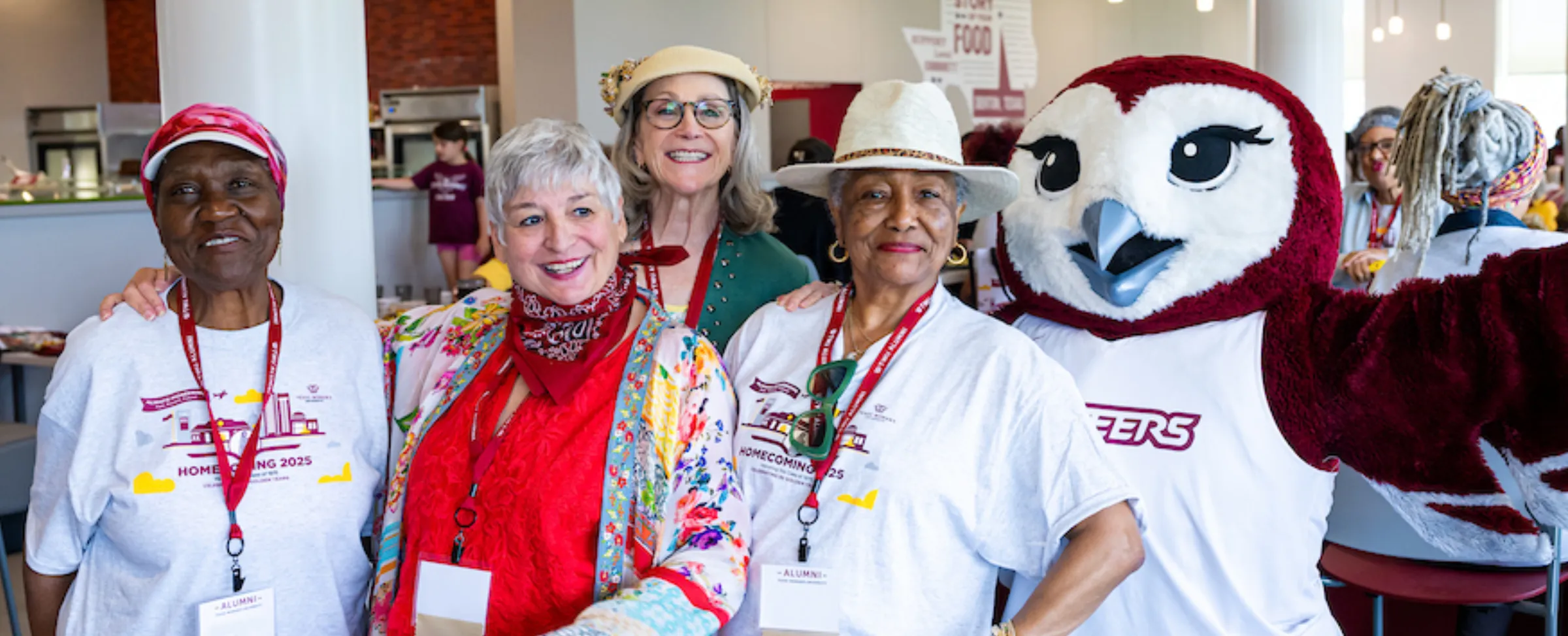 Four alumni pose with Oakley at the Homecoming Howdy Lunch.