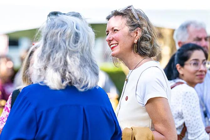 Candid shot of alumni gatheredoutdoors and conversing during university activites.