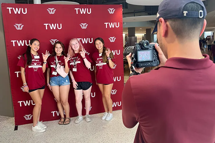 TWU Honors students posing in front of a fabric backdrop