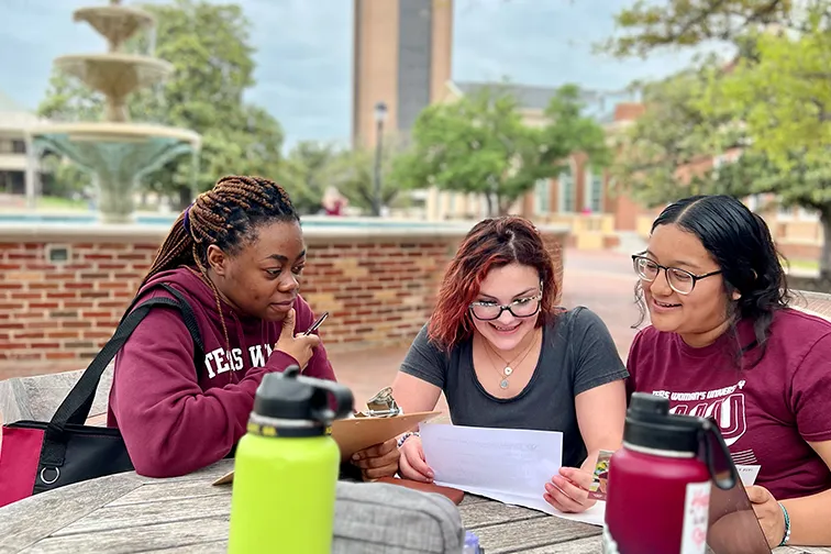 Honors students gathered around a laptop on a table