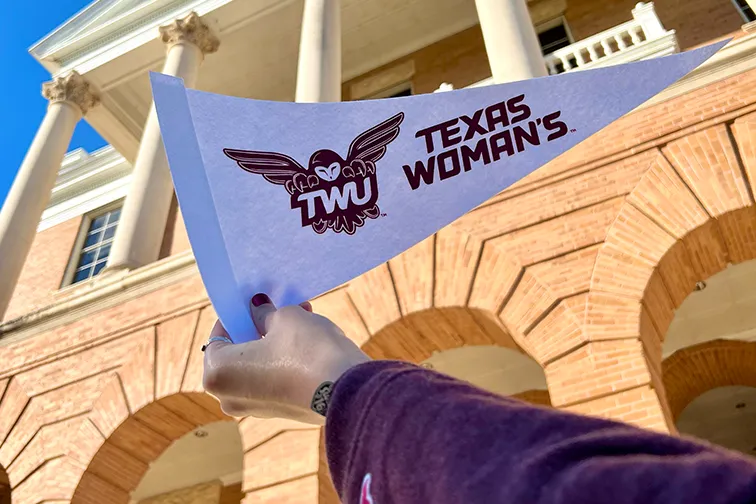 A TWU staff member holding up a Texas Woman