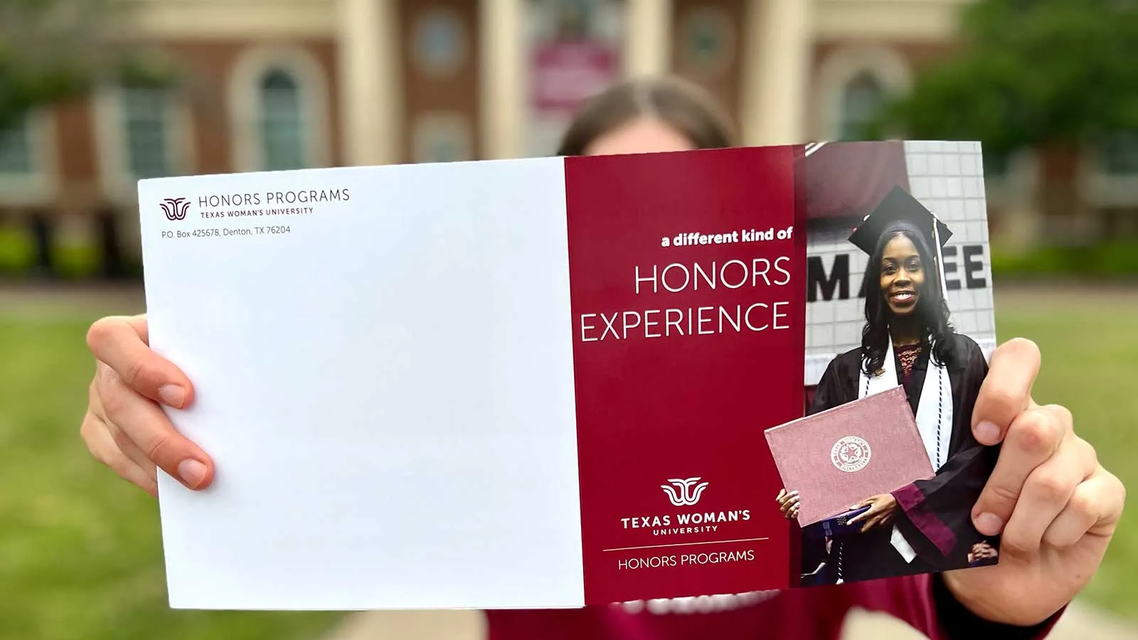 A TWU Honors student holding a brochure that reads 