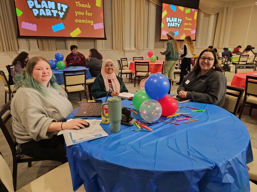 Students smile sitting around table