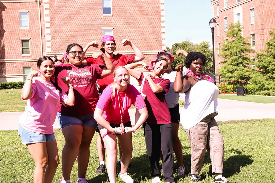 Students pose for a group photo outside on a sunny day