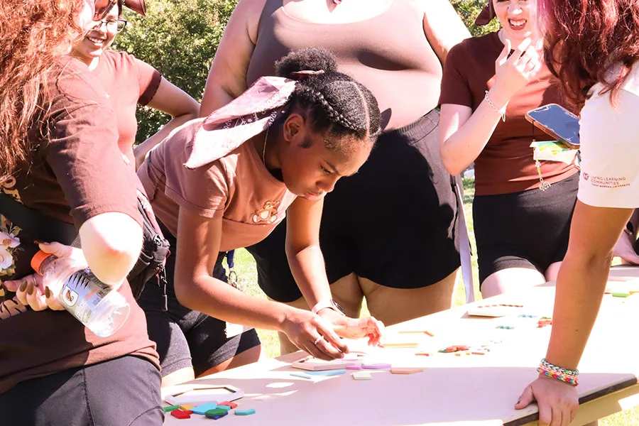 Student hunches over table solving a puzzle