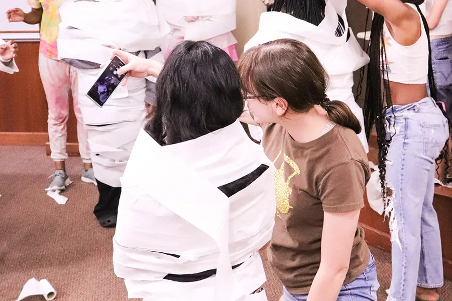 Student takes selfie with other student covered in toilet paper