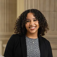 Girl with blazer and patterned shirt smiles at camera.