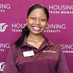 Girl in TWU polo shirt smiles in front of maroon backdrop.