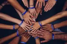 A group of clasped hands with arms radiating outward in a circle