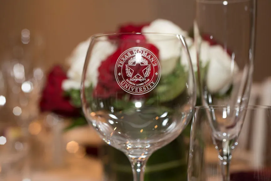 a close-up of a TWU wine glass with the university seal etched on it
