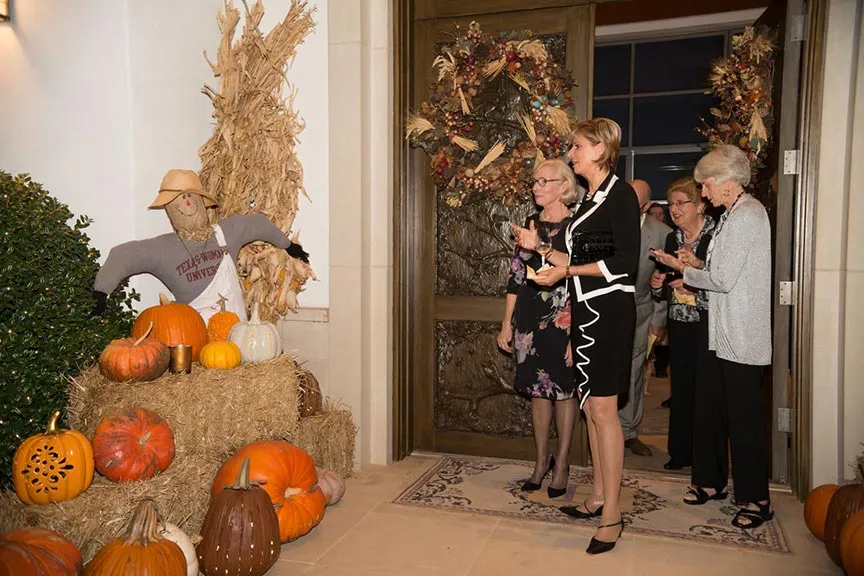 Chancellor Feyten admires an autumn display of a scarecrow and pumpkins
