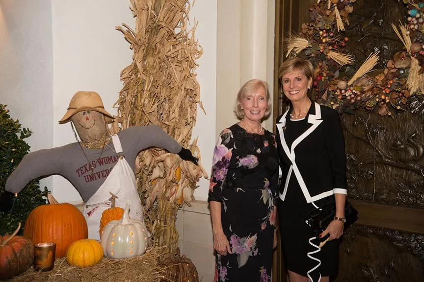 Chancellor Feyten has her photo taken with Sue Bancroft by the autumn display scarecrow