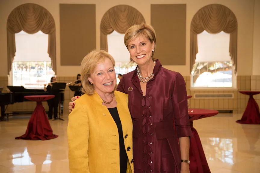 Chancellor Feyten and a woman in a yellow jacket smile together for a photo