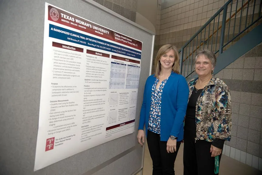 two women smile next to a presentation poster