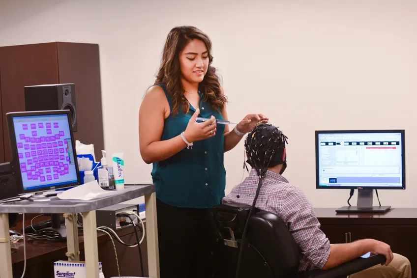 TWU health informatics student Andrea Mapua prepares a subject for testing in the research lab at the University of Texas at Dallas Center for Brain Health. 