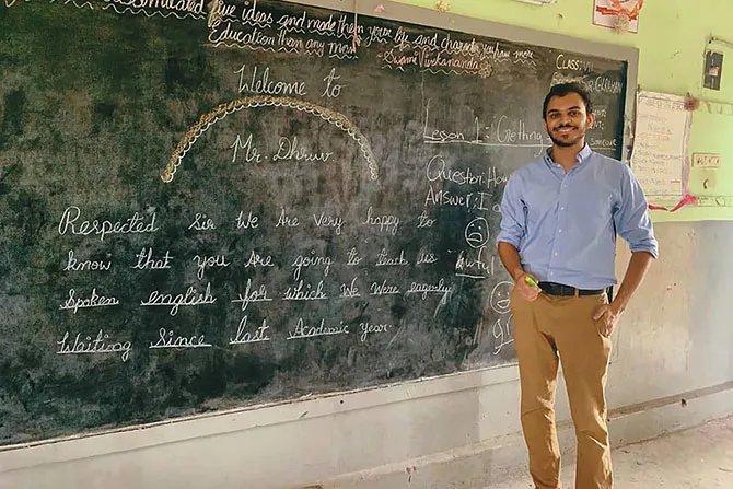 A Fulbright student stands in front of a chalkboard