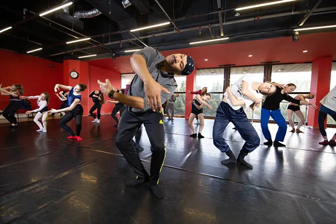 A group of students perform a choreographed dance number in a studio