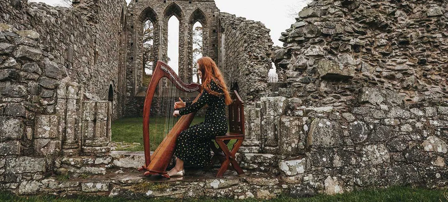 TWU student Hannah Flowers plays the harp at Inch Abbey, Ireland