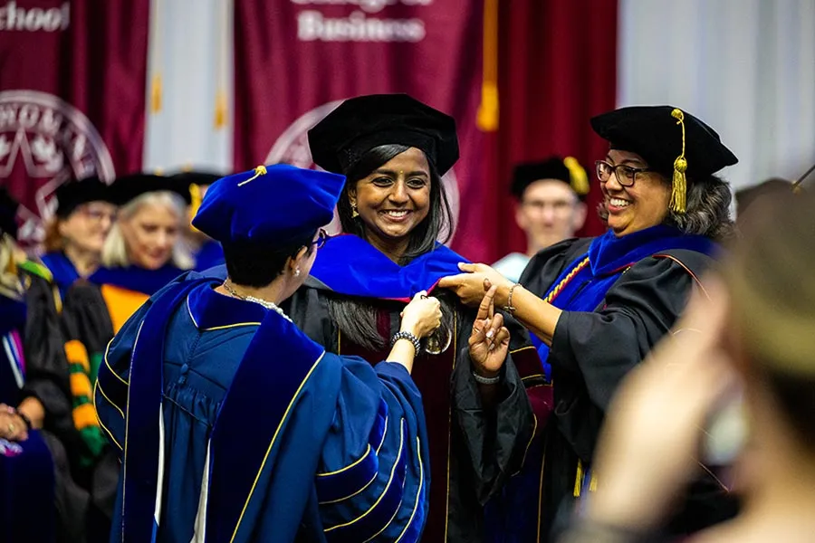 A hooding ceremony for an international TWU graduate student wearing the scholar medallion