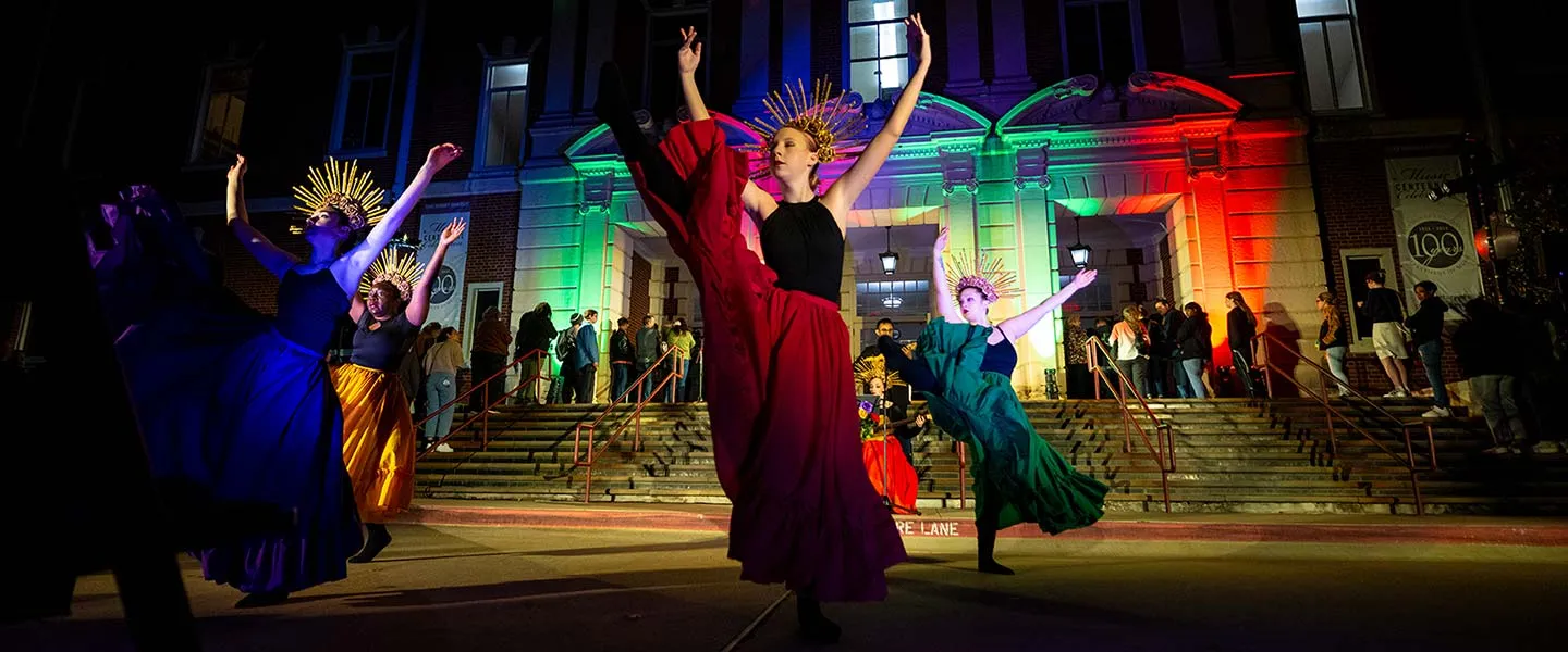 Dancers in international dress perform on the Pioneer Circle at night