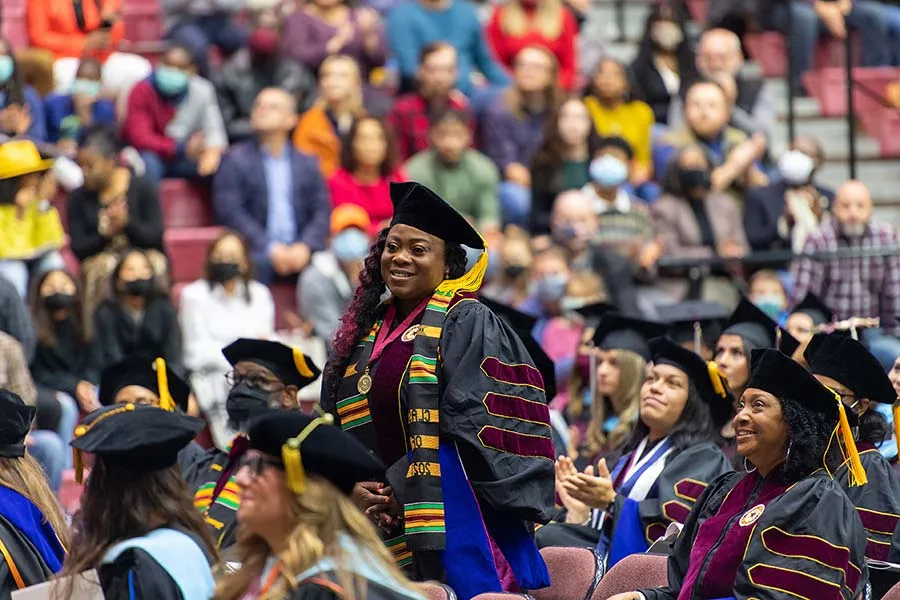 A TWU international graduate wearing her medallion stands amidst the crowd