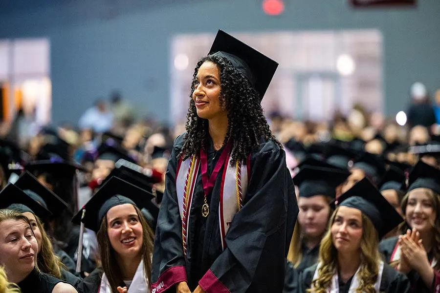 A student stands during Commencement wearing the medallion with her cap and gown