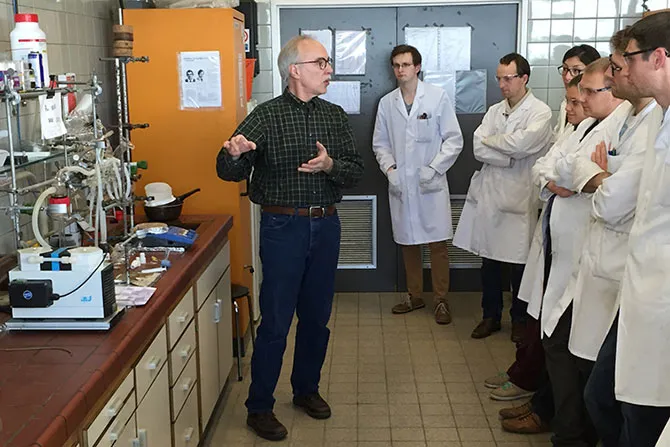 An instructor explains the use of lab equipment to students gathered around him.