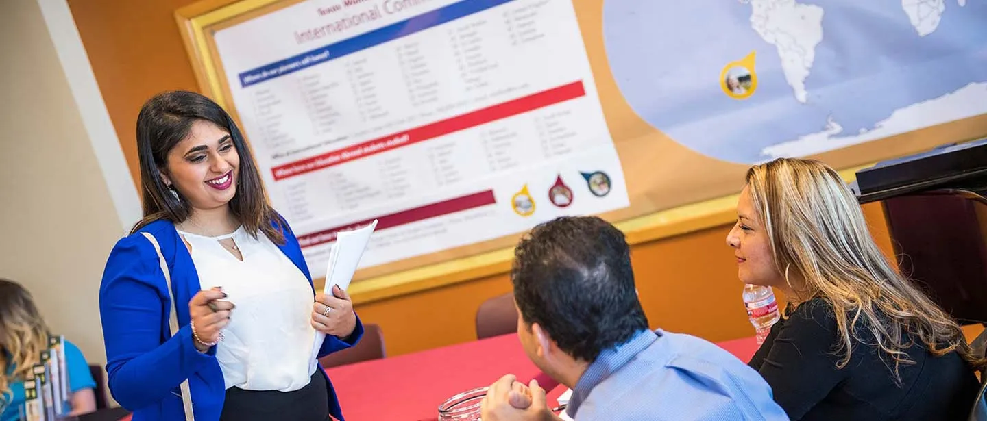 A young woman speaks to two prospective employers at a hiring fair