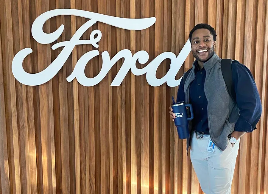 Chuk Anyanwu stands next to a large Ford logo