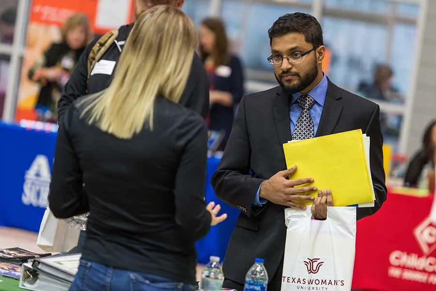 A TWU student at a career fair talking to an employer.