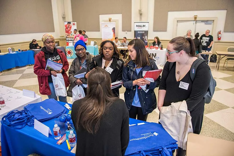 A group of students talk at a career fair with an employer.