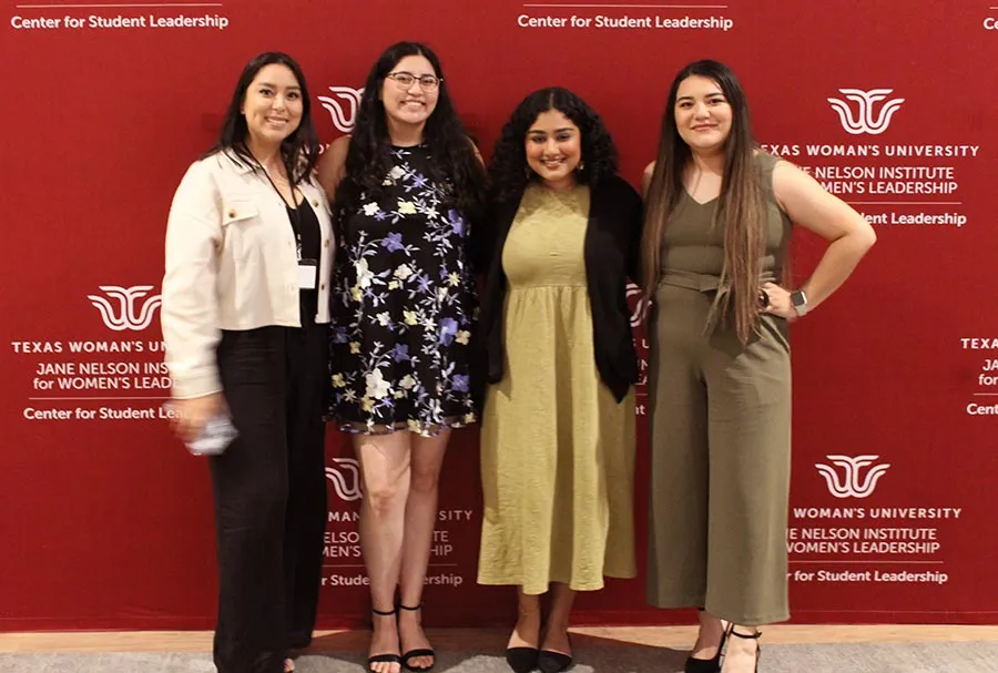 Aesha Desai with other students against a backdrop for the Jane Nelson Institute for Women's Leadership