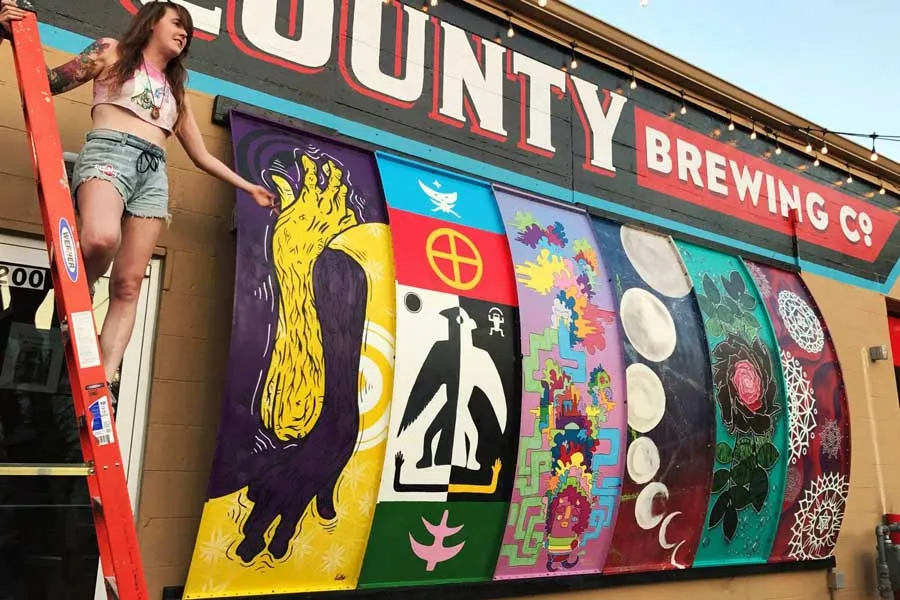 Katie Mont poses with a mural she painted outside Denton County Brewing Company.